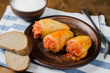 Stuffed peppers with rice and minced meat stew in tomatoes, rye bread. Rustic food.