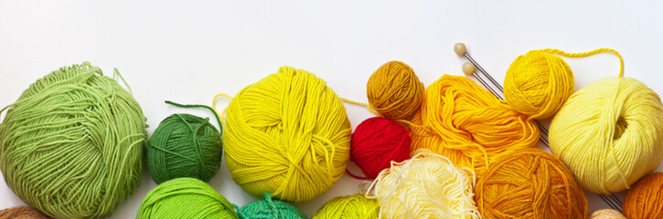 Panoramic top view on colorful balls of yarn for hand knitting on a white background. On top empty...