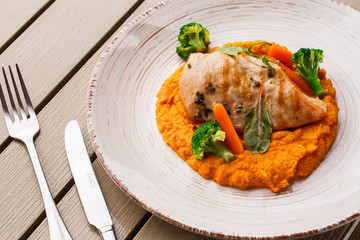 Chicken breast steak with carrot puree baby carrot and broccoli. Grilled chicken slice with baby carrot puree. wooden backgrounf