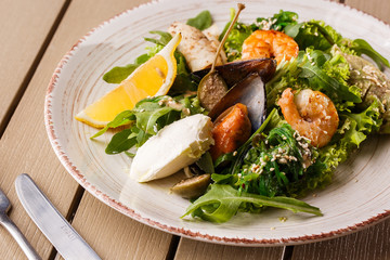 Healthy Salad. Recipe for fresh seafood. Grilled shrimps, mussels and squid, fresh salad lettuce and avocado puree. Healthy Eating. Wooden background
