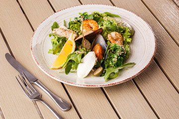 Healthy Salad. Recipe for fresh seafood. Grilled shrimps, mussels and squid, fresh salad lettuce and avocado puree. Healthy Eating. Wooden background