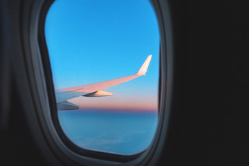 View from aircraft window on wing and pink colors of a majestic sunset