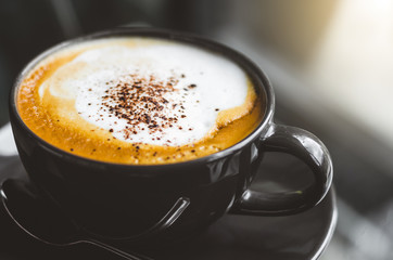 close up modern hot black coffee the cappuccino on dark background with coffee bubble foam pattern and texture in black cup looking and feel so delicious on glasses table in coffee shop.