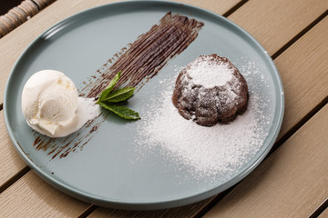 Delicious fresh fondant with hot chocolate and ice cream and mint served on plate. Lava cake recipe. Wooden background.