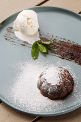 Delicious fresh fondant with hot chocolate and ice cream and mint served on plate. Lava cake recipe. Wooden background.