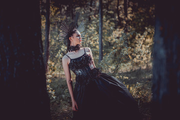 Naklejka premium selective focus of beautiful woman in black witch costume standing between trees