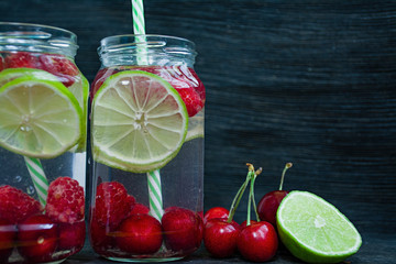 Refreshing summer drink with fruit. Drink made from cherry, raspberry, lime. Dark wooden background. Space for text.