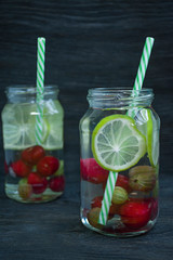 Fototapeta na wymiar Refreshing summer drink with fruit. Drink made from cherry, gooseberry, lime. Dark wooden background.