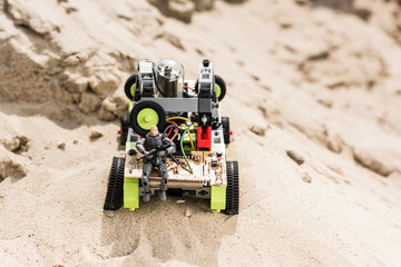 plastic toy soldier sitting with gun on vehicle on sand dune