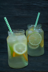 Refreshing summer drink from citrus fruits. Drink from lime, lemon, orange. Dark wooden background.