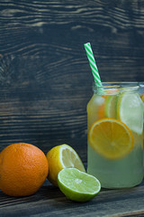 Refreshing summer drink from citrus fruits. Drink from lime, lemon, orange. Dark wooden background. Space for text.