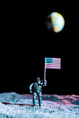 toy soldier holding national american flag in space with planet Earth on black background