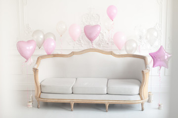 Luxury living room with sofa and stucco on the walls decorated with balloons for the holiday. Selective focus.