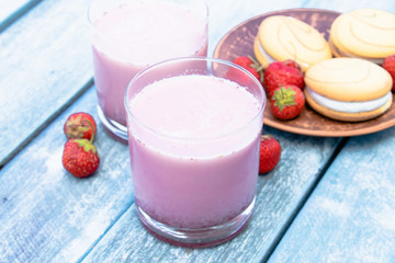 Cocktail with milk and berries club in a glass against the background of blue boards.