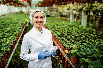 Portrait of happy female biologist standing in a plant nursery. - obrazy, fototapety, plakaty