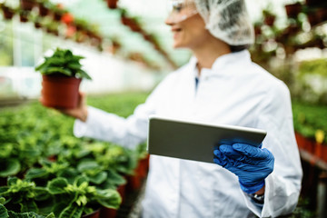 Close-up of biologist using digital tablet while working in a greenhouse.