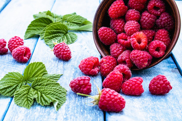 Fresh raspberry with leaves on a blue boards background. Selective focus.