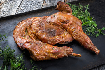 Gegrilltes halbes Zicklein mit Schulter und Keule garniert mit Bouquet Garni als Draufsicht auf...