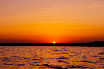 Fototapeta premium Sunset sky background. Dramatic gold sunset sky with evening sky clouds over the sea. Stunning sky clouds in the sunrise. Sky landscape. Panoramic sky view.