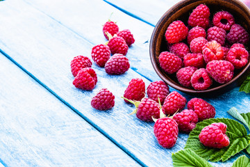 Fresh raspberry with leaves on a blue boards background. Selective focus.