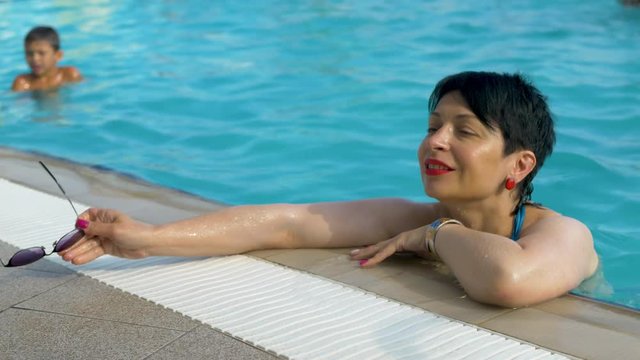 gorgeous woman relaxing at swim poolside. Chillin in water park during hot summer day