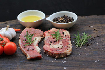 Raw beef steak with rosemary and vegetables on wooden dark background, food meat or barbecue