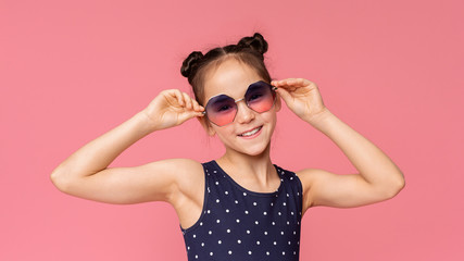 Cute little girl in stylish sunglasses enjoying summer time