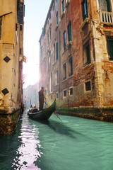 Fototapeta na wymiar Gondolier rowing gondola in canal