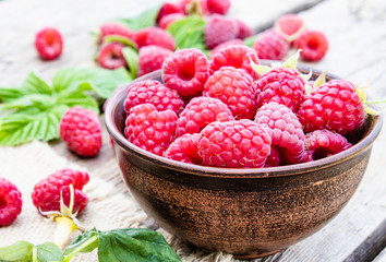 Fresh raspberry with leaves on the background of old boards. Selective focus.