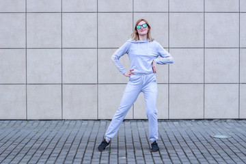 The girl is blonde in a gray sports suit. Street clothing. Sport. Advertising. Fashion and style. Trends. Mockup. Copyspace