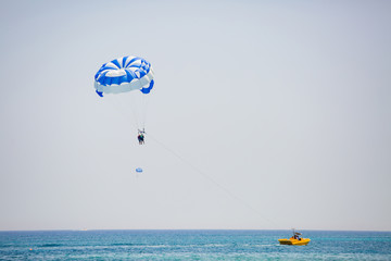 Couple of tourists flies on a blue and white parachute