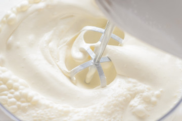 Whipping cream with a mixer. Bubbles on cream