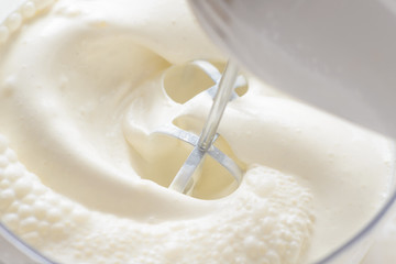 Whipping cream with a mixer. Bubbles on cream