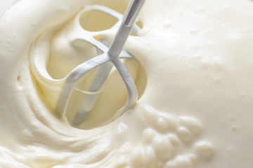 Whipping cream with a mixer. Bubbles on cream