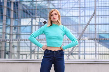 The girl is blonde in a blue croptop. Street clothing. Sport. Advertising. Fashion and style. Copyspace. Mockup