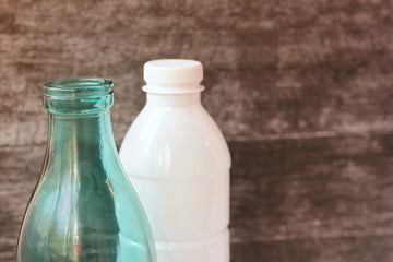 Glass milk bottle and plastic bottle. Reusable packaging. Empty space for text.
