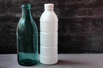 Glass milk bottle and plastic bottle. Reusable packaging. Empty space for text.