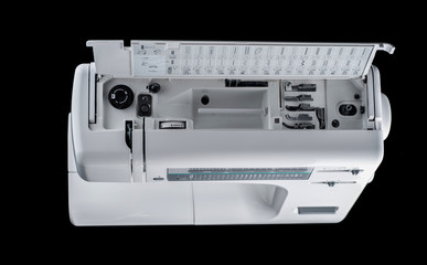 Electromechanical modern sewing machine white plastic top view on an additional technical department on a black background, isolate