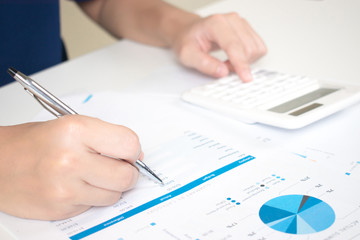 Close up of the accountant's hand is calculating the expense data in the graph to make money at work.