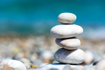 Stones pyramid on pebble beach with blur sea background. Travel and relax concept