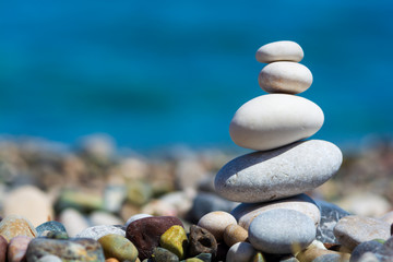 Fototapeta na wymiar Stones pyramid on pebble beach with blur sea background. Travel and relax concept