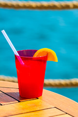 Fruit cocktail on wood with blur sea background. Travel and relax concept