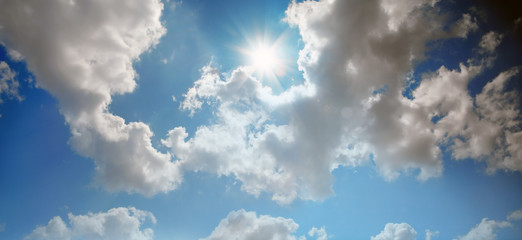 conceptual background image of blue sky with clouds and shining sun