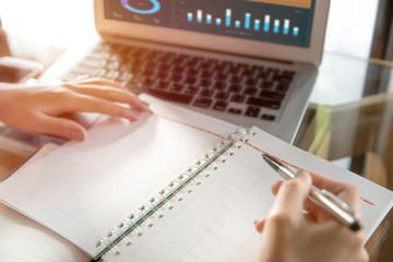Young business woman writing in calendar notebook.