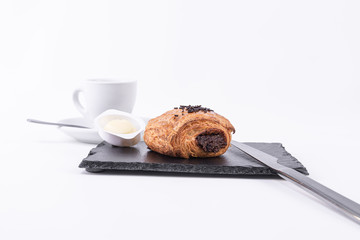 Hot coffee, fresh butter and a roll of puff pastry filled with chocolate