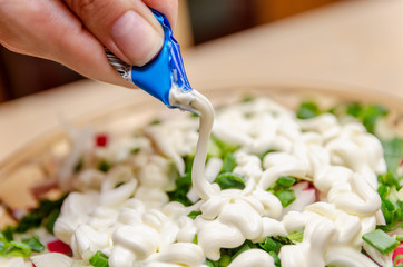 Obraz na płótnie Canvas Women's hands dressing vegetable salad with mayonnaise close-up. Water the vegetable salad with mayonnaise