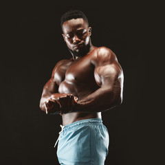 Fototapeta na wymiar African bodybuilder showing biceps in black studio