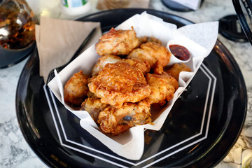Deep fried battered chicken on paper and black plate