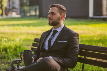 Fototapeta premium Elegant businessman enjoys drinking coffee while sitting outdoor.Toned image.