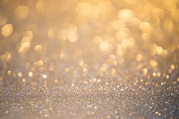 Silver glitter christmas abstract background in golden light. Defocused sequin light.